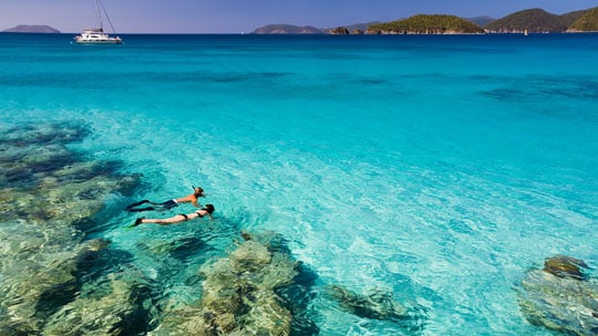 A man and a woman snorkel in clear water.